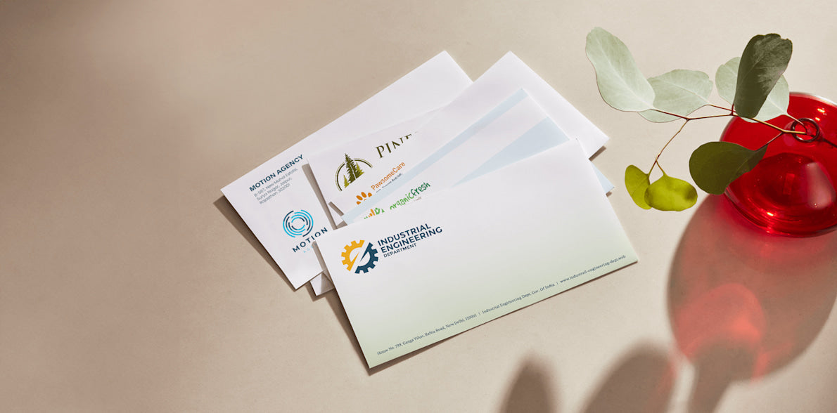 Three business cards with logos on a beige surface with a red vase and green leaves.